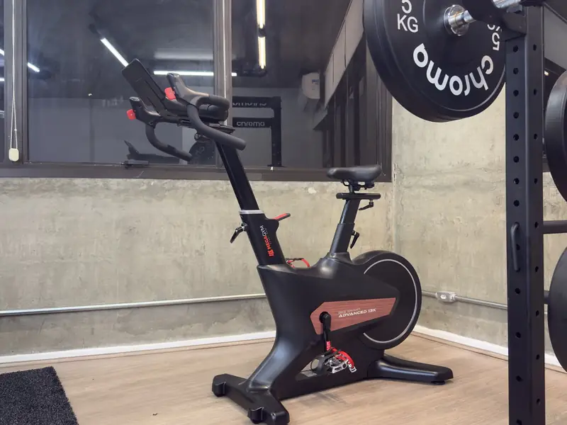 Bicicleta ergométrica ao lado do rack com anilhas na Joelho Mais Fisio