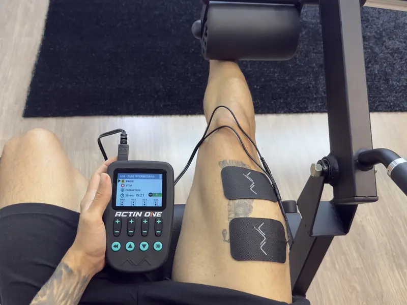 Aparelho de eletroestimulação com eletrodos na coxa durante exercício na cadeira extensora