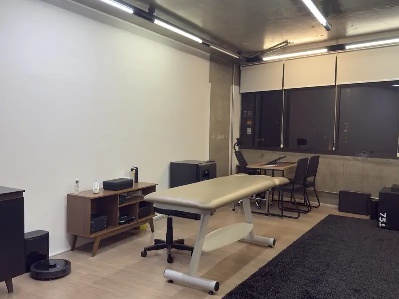 Sala de atendimento da Joelho Mais Fisio com maca, mesa de consulta e caixas de salto